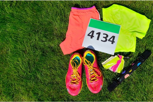 Flat lay of tropical running outfit including technical shirt, shorts, and cap.