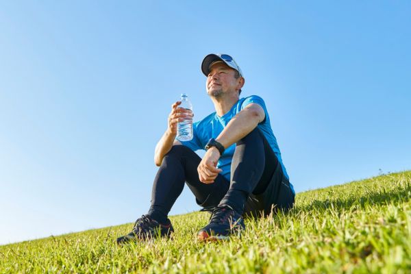 Finisher relaxing on a field of green grass with a bottle of water.
