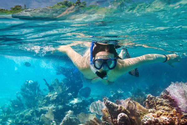 Tourists snorkeling in crystal-clear waters near Sapi Island, one of many beautiful Sabah attractions.